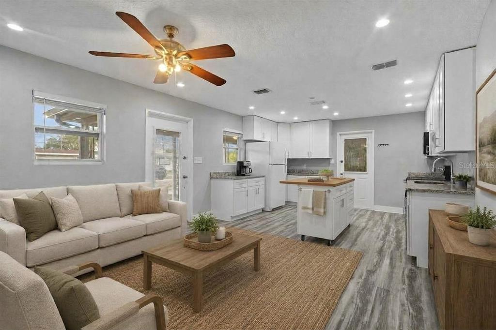 A kitchen with white cabinets, stainless steel appliances, and wood-look flooring in an open room — 4402 W TRILBY AVENUE, TAMPA, FL