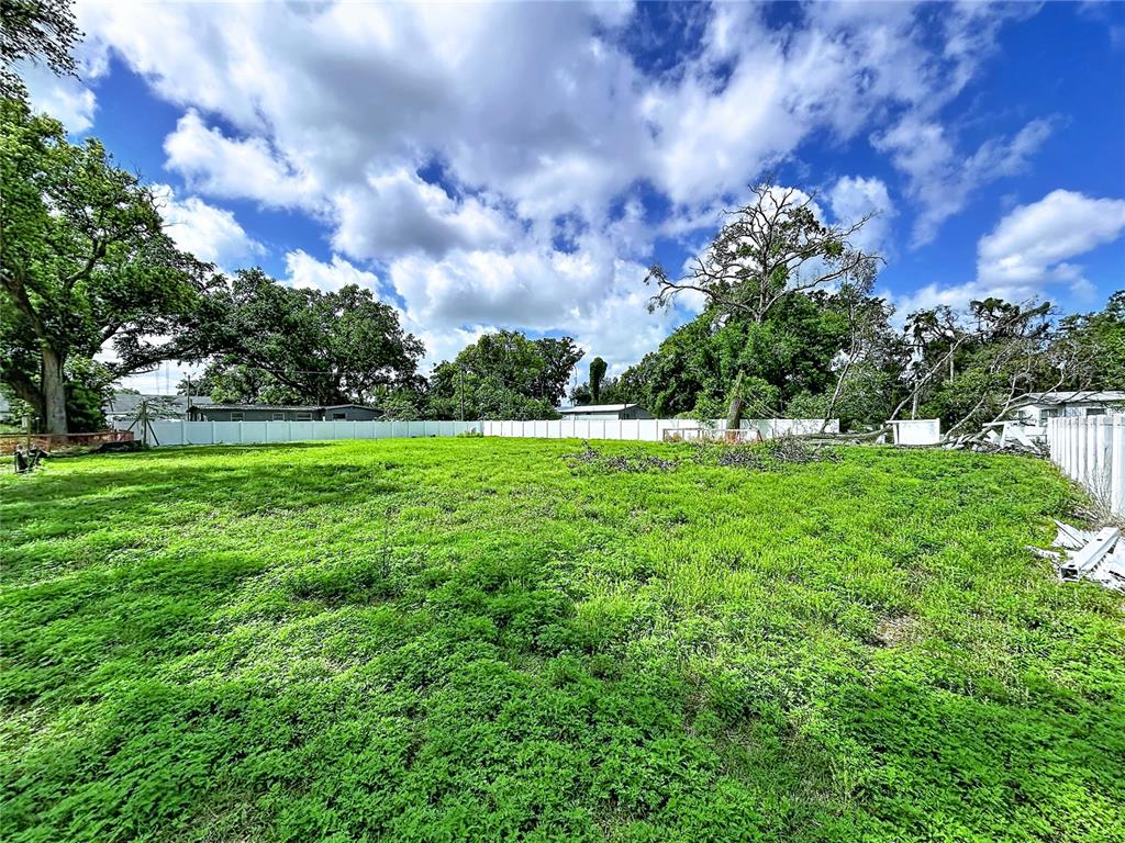 A large, grassy vacant lot is enclosed by a white vinyl privacy fence — ROBSON, SEFFNER, FL