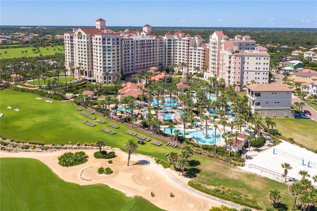 An aerial view shows a large resort hotel complex with pools, palm trees, and golf courses — 200 OCEAN CREST DRIVE UNIT 421, PALM COAST, FL