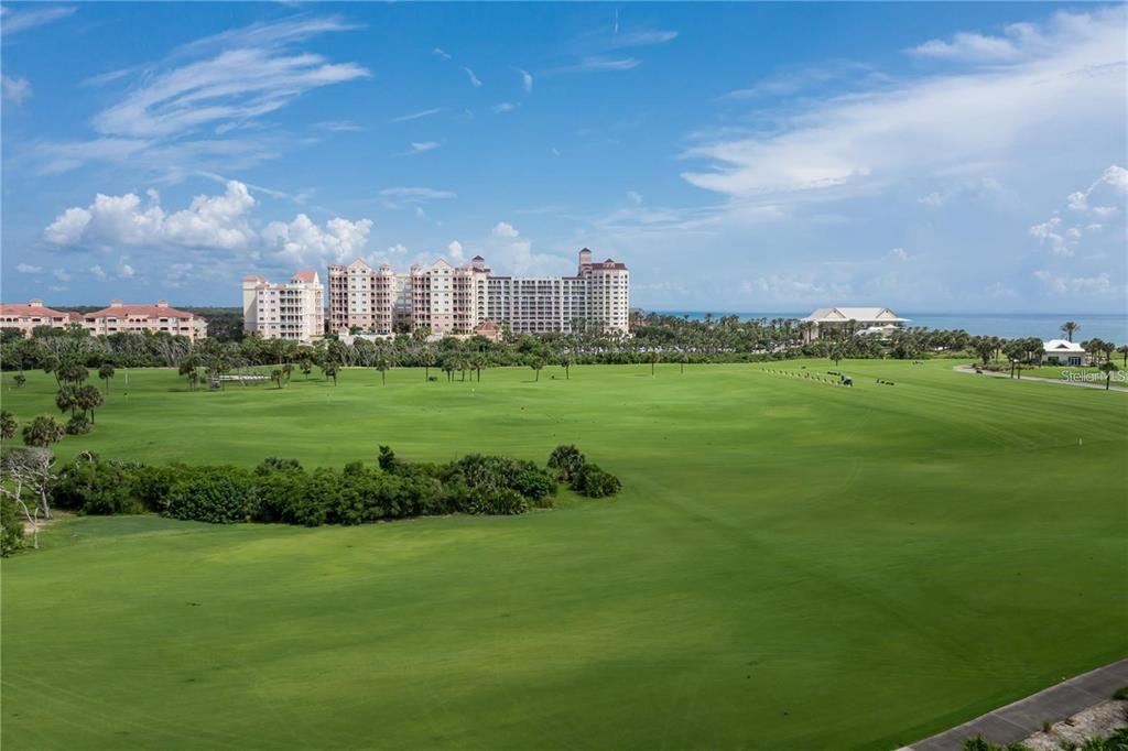 A view of a large green golf course with a multi-story resort building in distance — 200 OCEAN CREST DRIVE UNIT 421, PALM COAST, FL