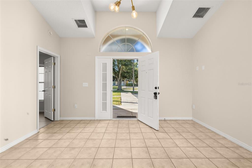An entryway with beige tile flooring, a vaulted ceiling, and an open front door — 3141 ENCLAVE COURT, KISSIMMEE, FL