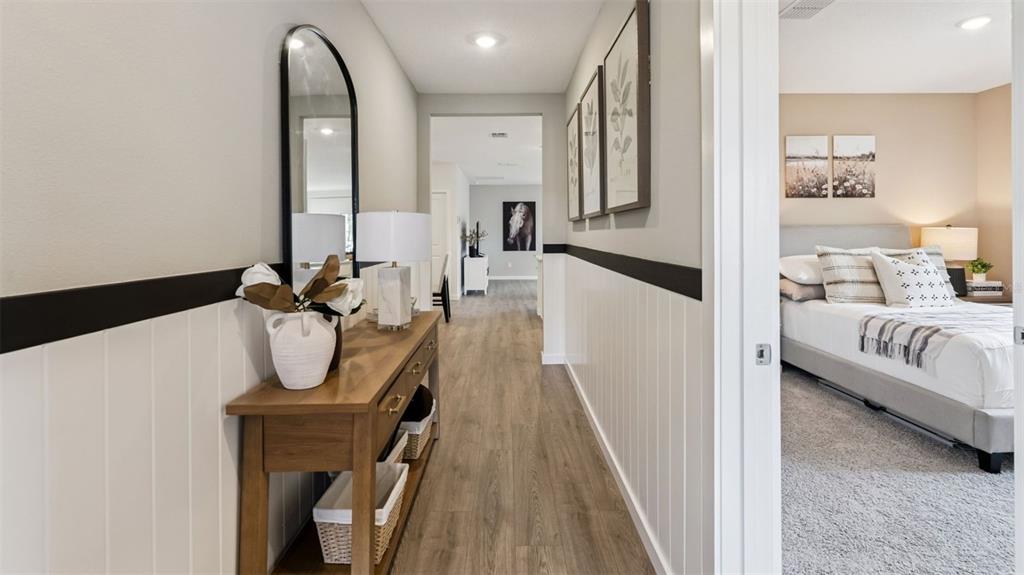 A hallway with wood-look flooring and wainscoting leads to a bedroom and another room — 1144 GULL DRIVE, APOPKA, FL