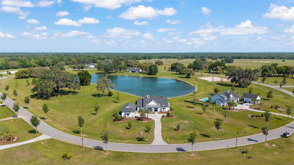 An aerial view shows a modern farmhouse with a pool near a large pond — 12902 SW 138TH LOOP, DUNNELLON, FL