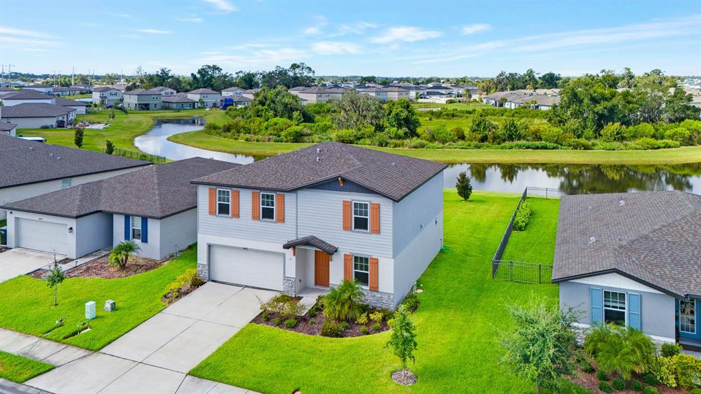 An aerial view of a two-story suburban house with a garage and a backyard pond — 10025 DAYBREAK GLEN, PARRISH, FL