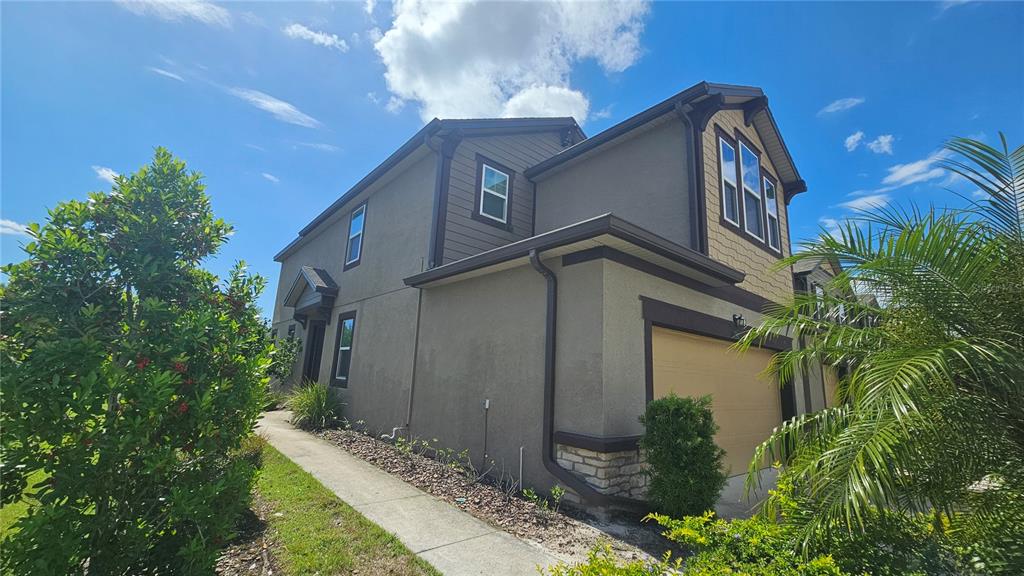 A two-story house with a tan garage, brown trim, and a concrete walkway — 11840 SKY ACRES TERRACE, BRADENTON, FL