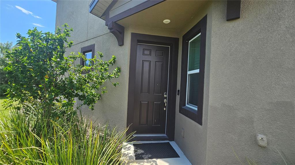 A dark brown front door with a window and a small porch area — 11840 SKY ACRES TERRACE, BRADENTON, FL