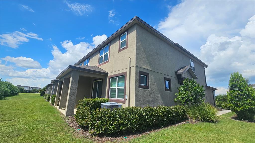 The exterior of a two-story tan stucco townhouse with a small patio and landscaping — 11840 SKY ACRES TERRACE, BRADENTON, FL