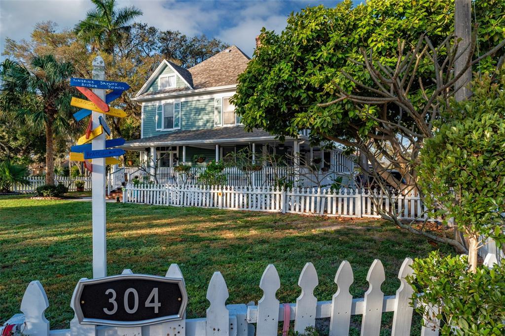 A two-story house with a white picket fence and a signpost in the front yard — 304 15TH STREET W, BRADENTON, FL