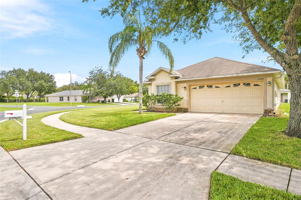 A single-story house with a beige exterior, a two-car garage, and a palm tree — 25928 CRIPPEN DRIVE, LAND O LAKES, FL