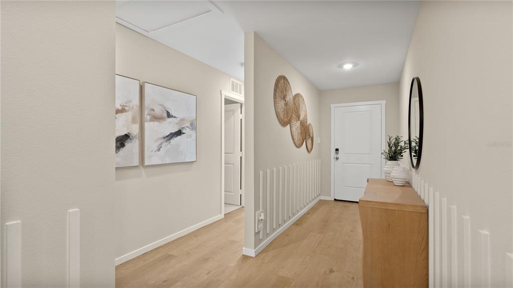 A bright entryway features light wood flooring, a white door, wall art, and a console table — 6124 SWAMP BAY DRIVE, EDGEWATER, FL