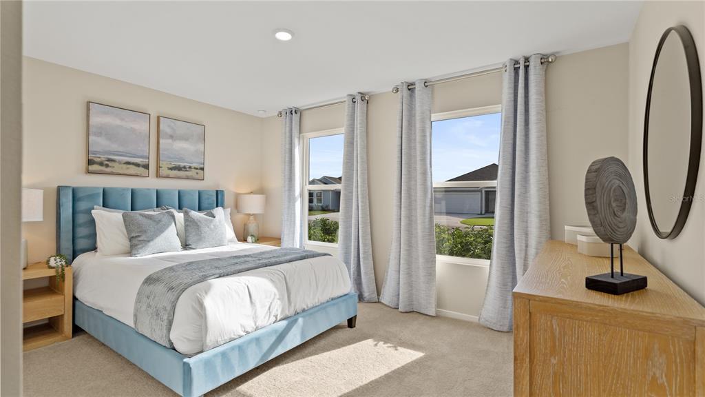 A bedroom features a blue upholstered bed, light wood furniture, and two windows with curtains — 6124 SWAMP BAY DRIVE, EDGEWATER, FL
