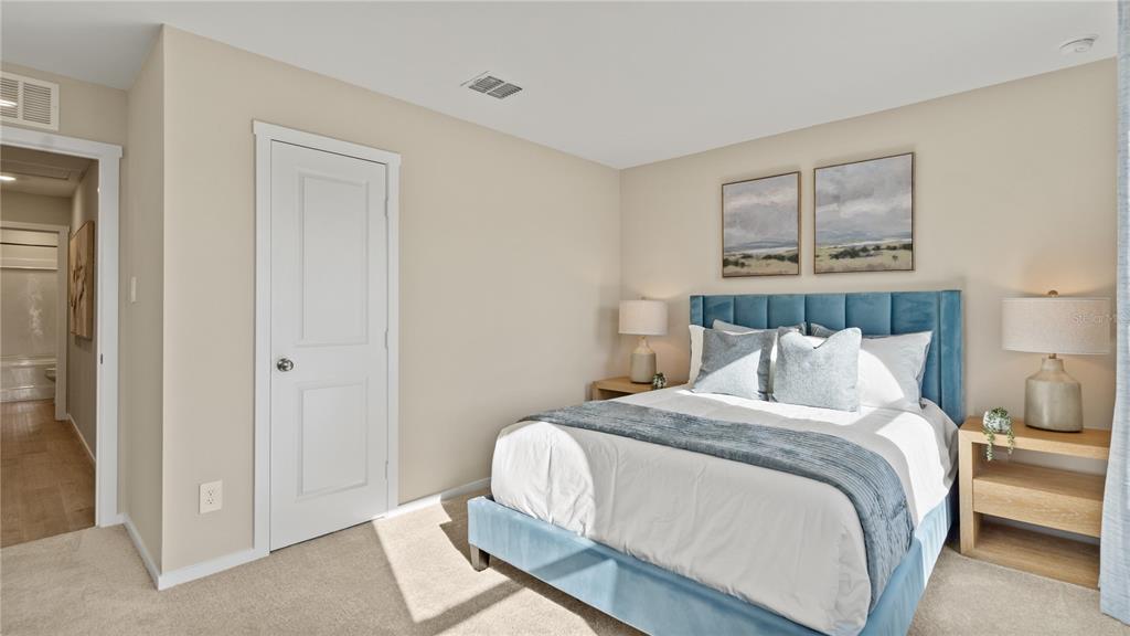 A bedroom features a blue upholstered bed, two nightstands with lamps, and a white door — 6124 SWAMP BAY DRIVE, EDGEWATER, FL