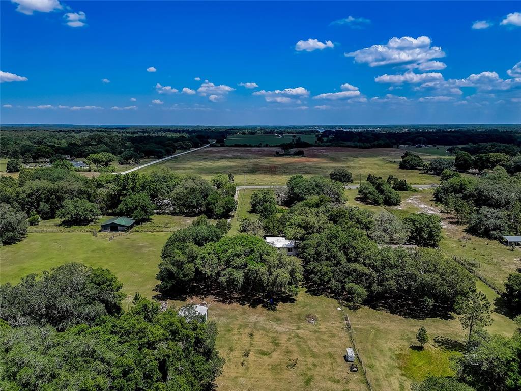 An aerial view shows a house and barn surrounded by trees and open pasture land — 7119 STATE ROAD 33, CLERMONT, FL
