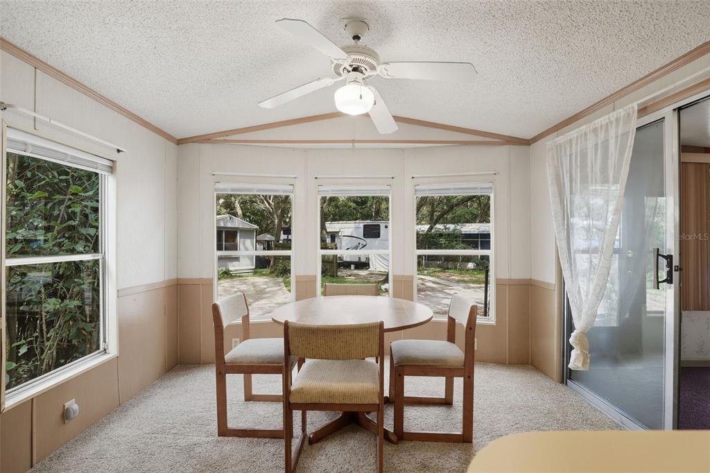 A dining area with a round table, three chairs, carpeted floors, and large windows — 3000 CLARCONA ROAD UNIT 362, APOPKA, FL