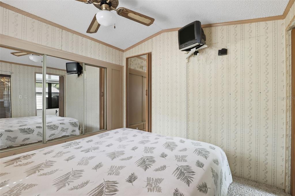 A bedroom features floral wallpaper, a ceiling fan, a bed, and mirrored closet doors — 3000 CLARCONA ROAD UNIT 362, APOPKA, FL