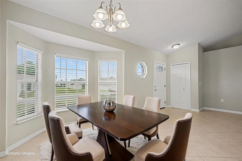 A dining room features a dark wood table, six chairs, and a bay window — 821 JARNAC DRIVE, KISSIMMEE, FL