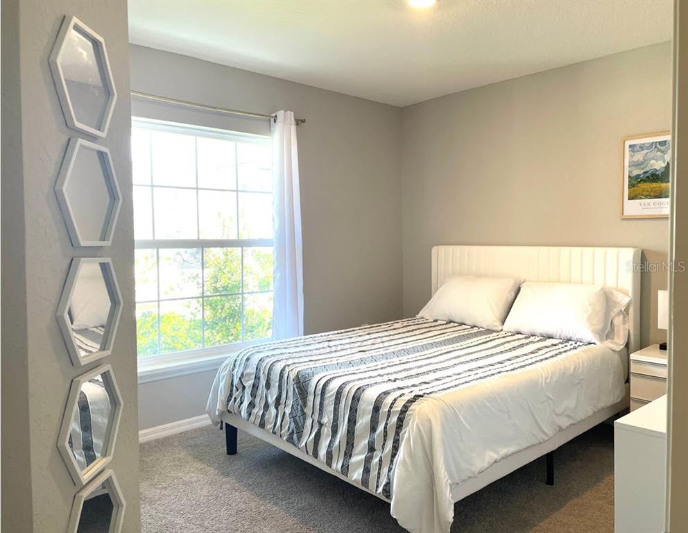 A bedroom features a bed with a striped comforter and a wall of hexagonal mirrors — 315 LILY LANE, DAVENPORT, FL