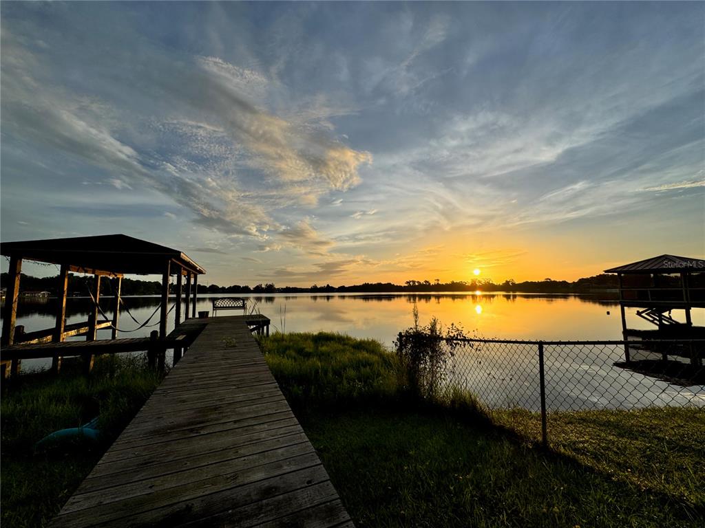 A wooden dock leads to a covered boat slip on a lake at sunset — 2510 CYPRESS GARDENS BOULEVARD, WINTER HAVEN, FL