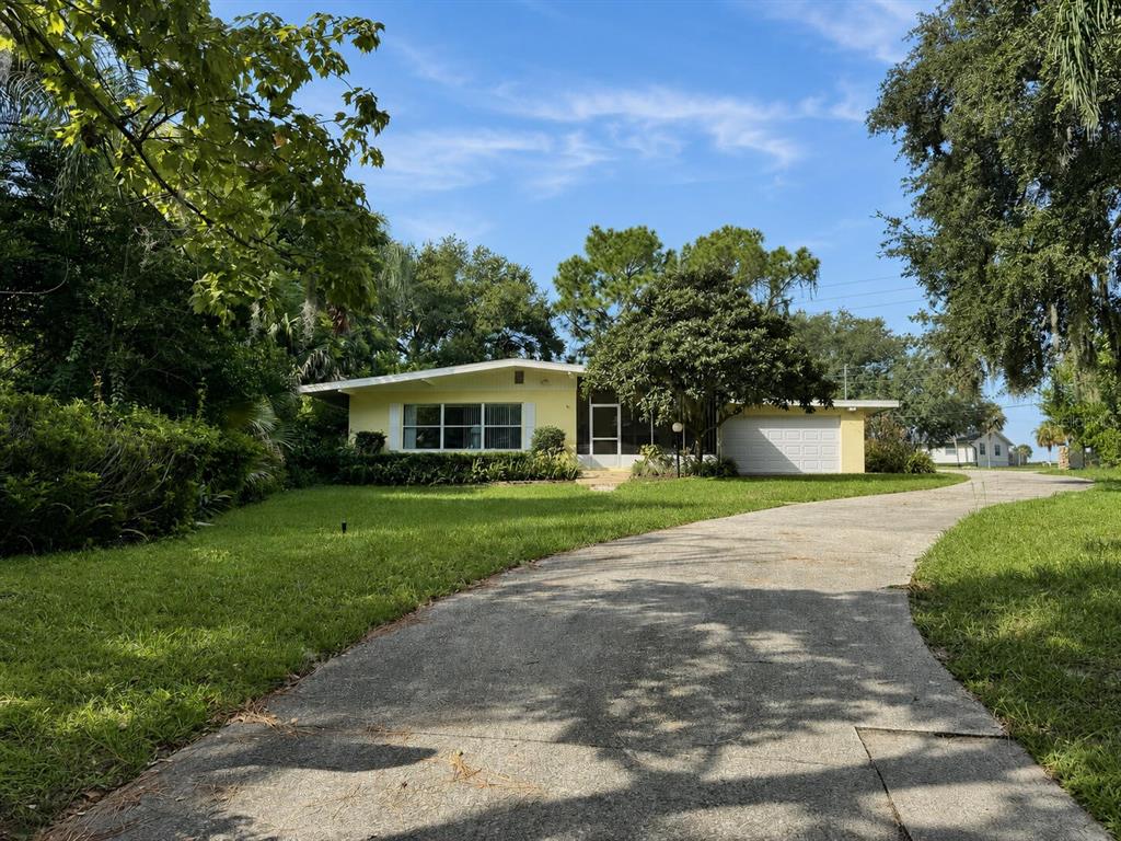 A single-story yellow house with a concrete driveway and a large tree in the front yard — 2510 CYPRESS GARDENS BOULEVARD, WINTER HAVEN, FL