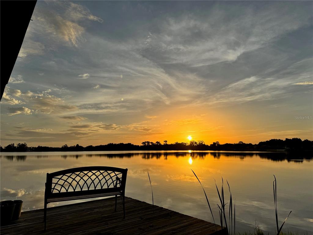 A metal bench sits on a wooden dock overlooking a lake at sunset — 2510 CYPRESS GARDENS BOULEVARD, WINTER HAVEN, FL