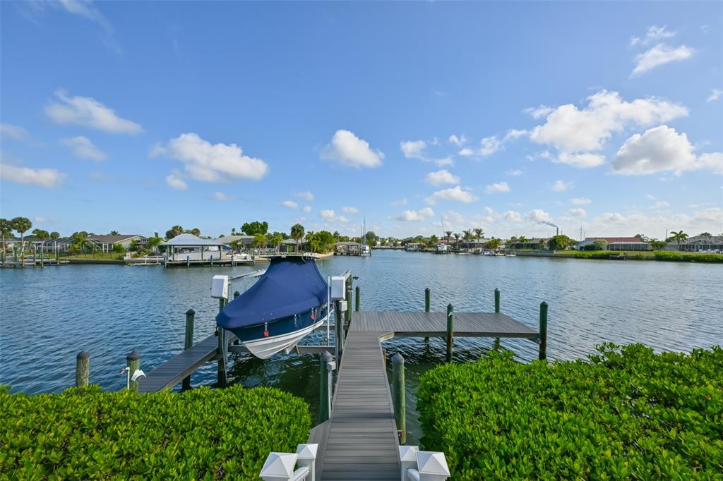 A boat on a lift is docked at a wooden pier overlooking a canal — 831 SYMPHONY ISLES BOULEVARD, APOLLO BEACH, FL