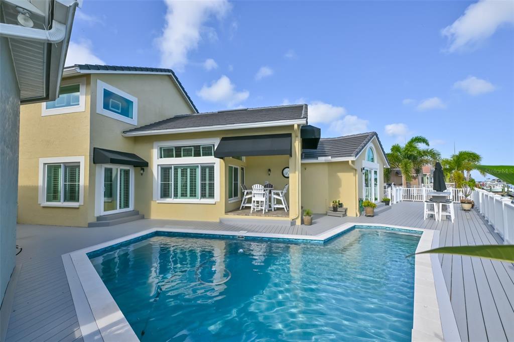 A yellow two-story house features a swimming pool and a deck with outdoor seating — 831 SYMPHONY ISLES BOULEVARD, APOLLO BEACH, FL