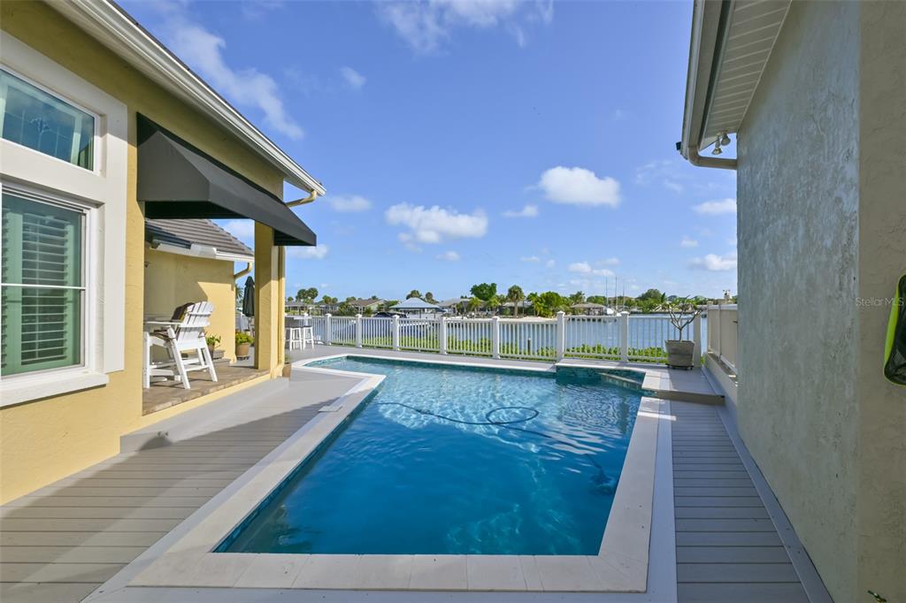 A rectangular swimming pool sits on a gray deck between two sections of a house — 831 SYMPHONY ISLES BOULEVARD, APOLLO BEACH, FL