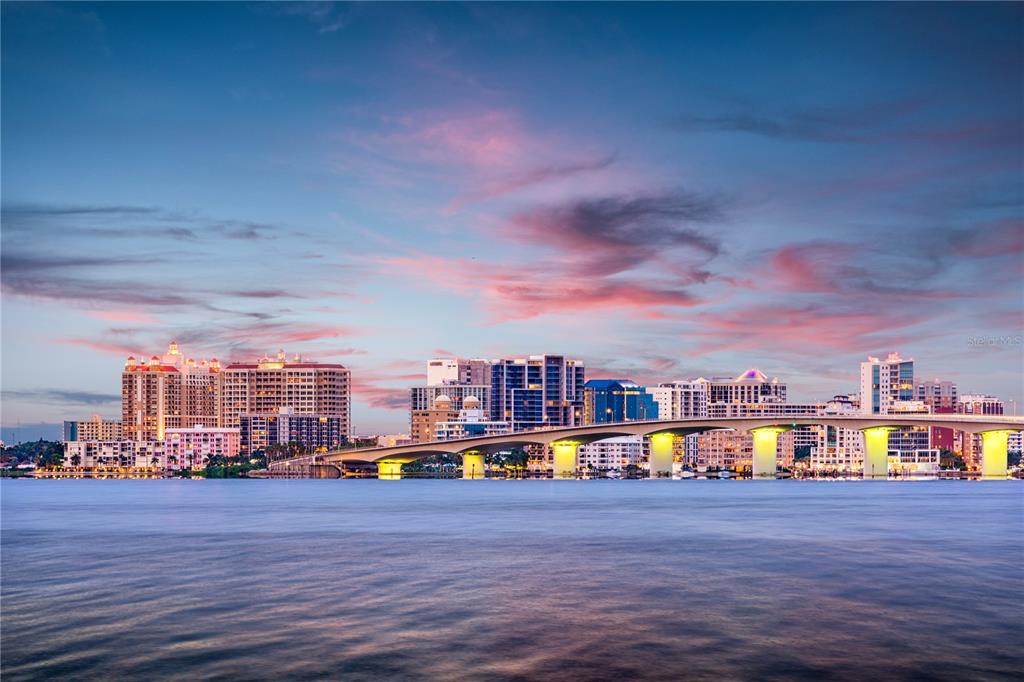 A bridge spans a body of water in front of a city skyline at sunset — 160 GARDEN LANE, SARASOTA, FL