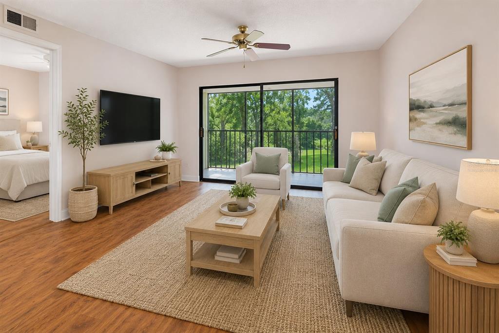 A living room features wood-look flooring, a beige sofa, a coffee table, and a balcony view — 130 NANCY DRIVE UNIT 37, OLDSMAR, FL