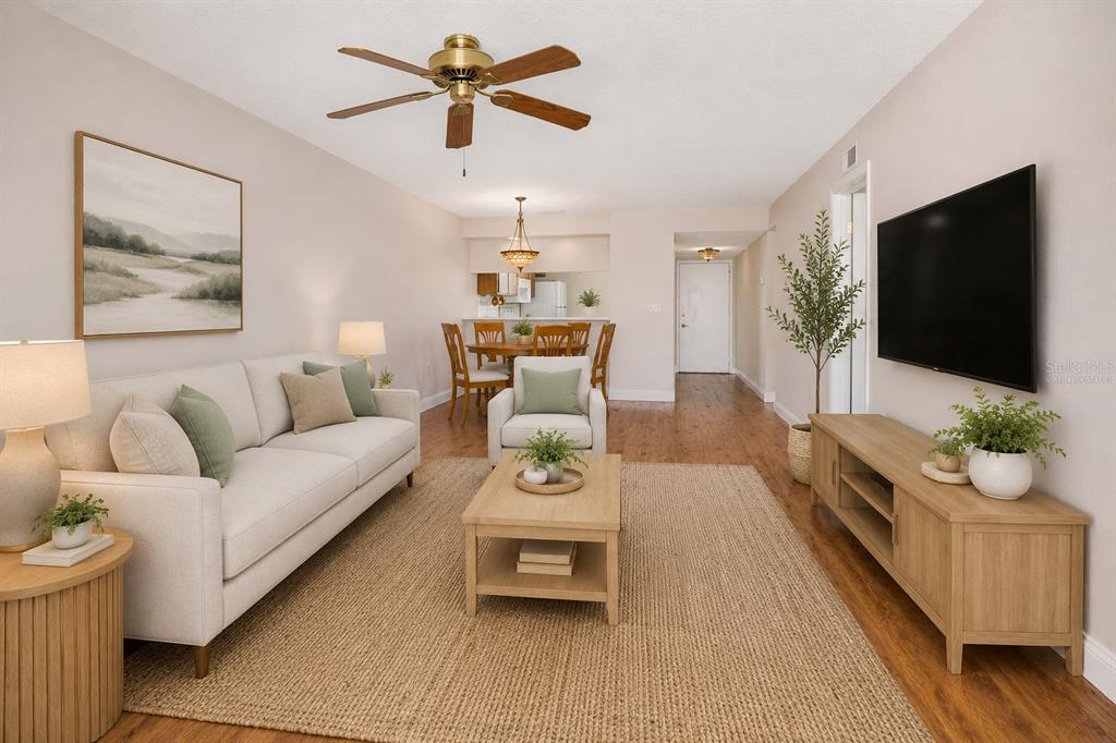 A living room with a sofa, coffee table, television, and dining area on wood flooring — 130 NANCY DRIVE UNIT 37, OLDSMAR, FL