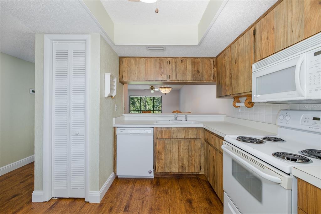 A kitchen features wood-grain cabinets, white appliances, a dishwasher, and a pass-through window — 130 NANCY DRIVE UNIT 37, OLDSMAR, FL