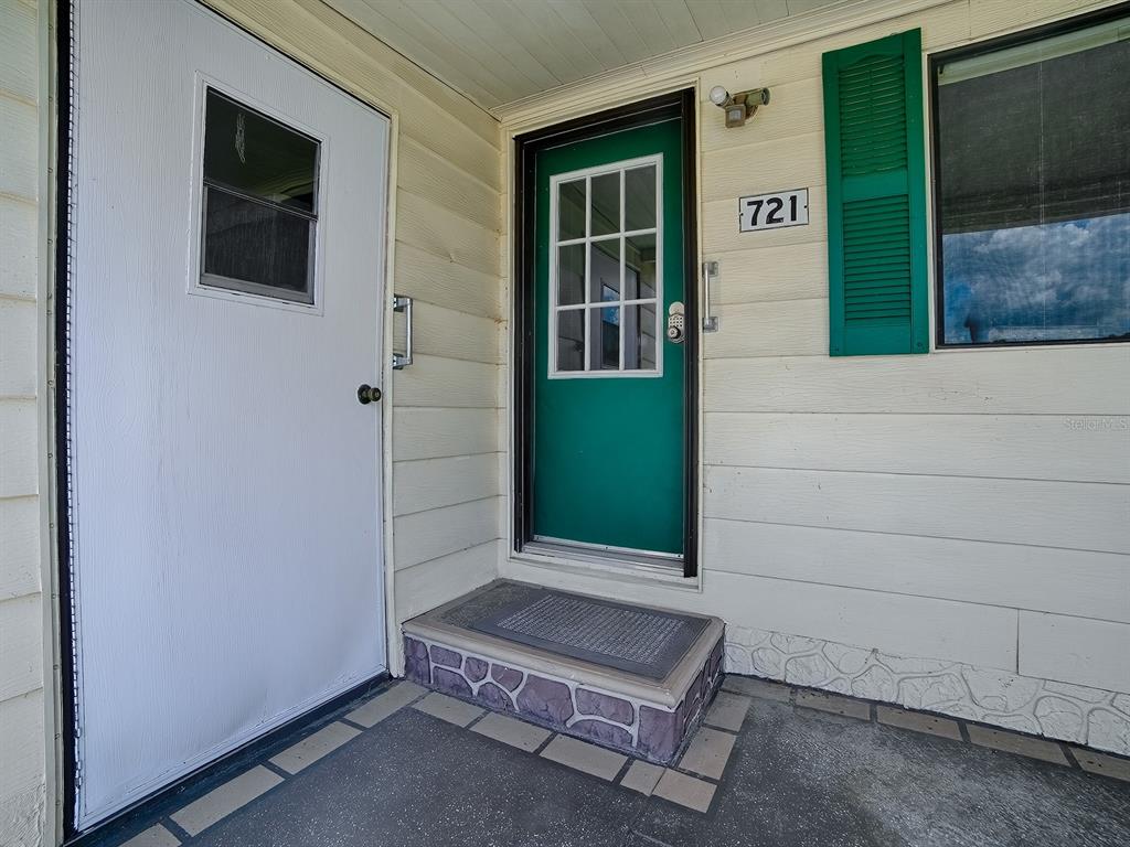 A white door and a green front door with a small step are visible — 721 SHARON DRIVE, THE VILLAGES, FL