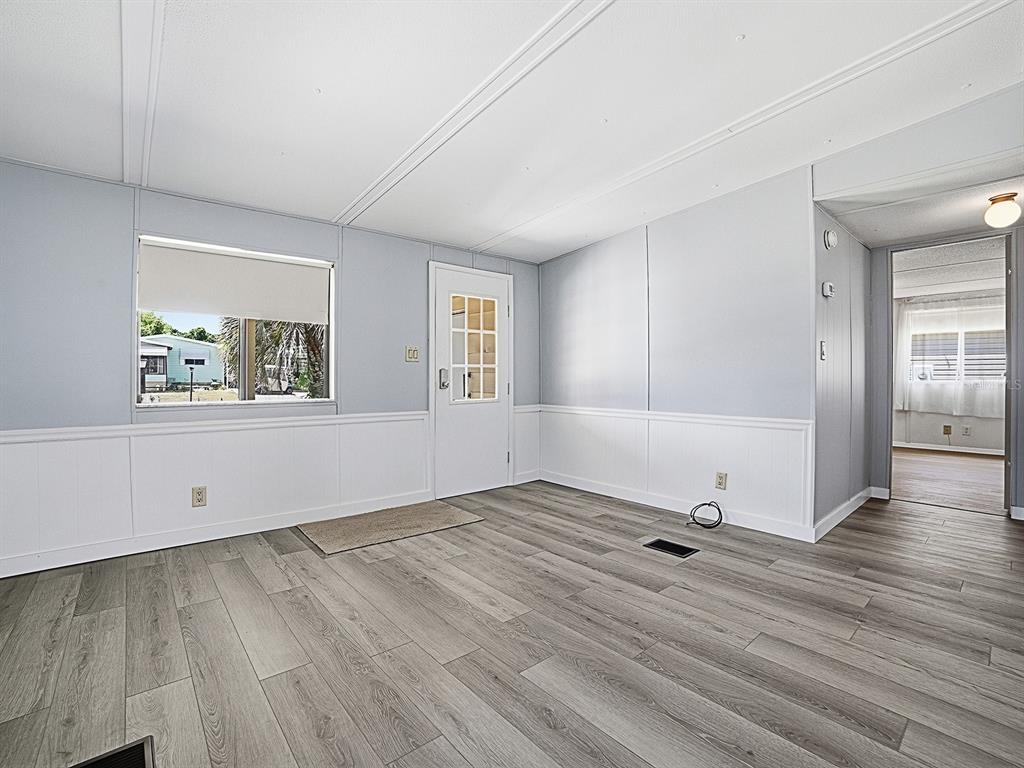 A living room with light gray walls, white wainscoting, and wood-look laminate flooring — 721 SHARON DRIVE, THE VILLAGES, FL