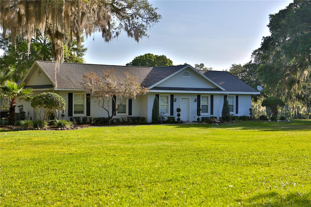 A single-story house with a gray roof and white siding sits on a large lawn — 13375 W HIGHWAY 318, WILLISTON, FL