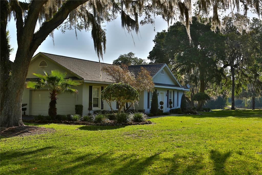 A single-story house with a garage and palm tree sits on a large grassy lawn — 13375 W HIGHWAY 318, WILLISTON, FL