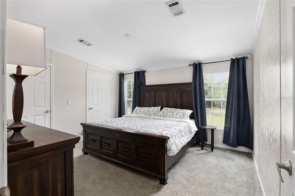A bedroom features a dark wood bed frame, patterned bedding, and navy blue curtains — 14785 SW 71ST AVENUE ROAD, OCALA, FL