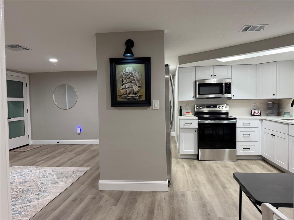 A hallway with light gray walls, wood-look flooring, and several white interior doors — 7220 FOX HOLLOW DRIVE, PORT RICHEY, FL