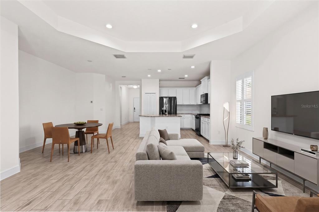 An open-concept living and dining area features light wood-look tile flooring and white cabinetry — 13506 CIRCA CROSSING DRIVE, LITHIA, FL