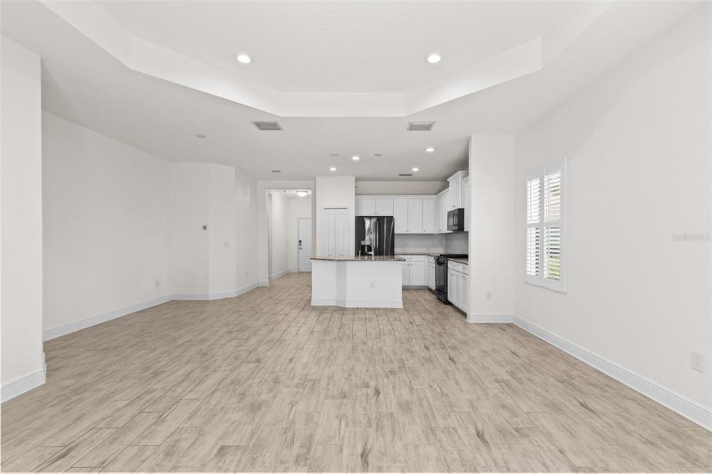 An open-concept kitchen and living area with light wood-look tile flooring and white cabinetry — 13506 CIRCA CROSSING DRIVE, LITHIA, FL