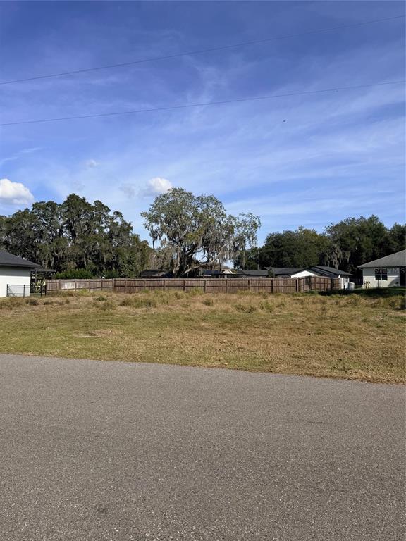 A vacant, grassy residential lot sits behind a wooden fence under a clear blue sky — 1707 TWIN LAKE DRIVE, GOTHA, FL