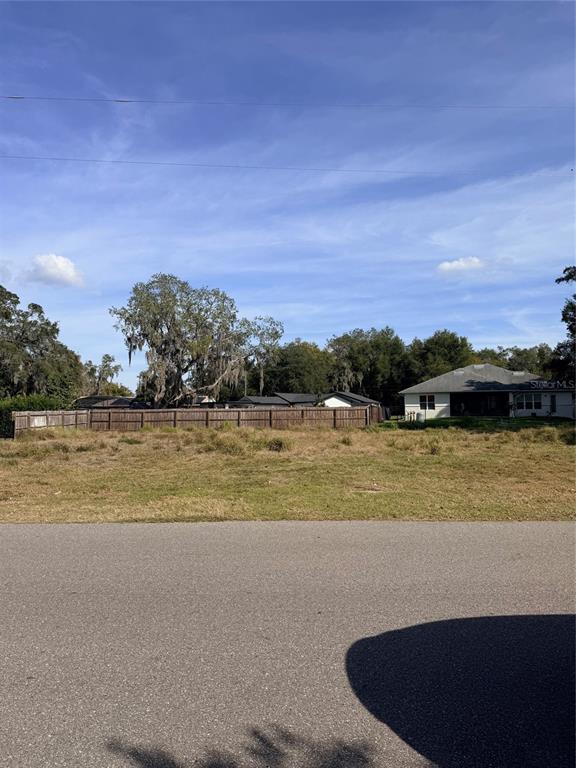 A vacant, grassy residential lot sits in front of a wooden fence and neighboring houses — 1707 TWIN LAKE DRIVE, GOTHA, FL