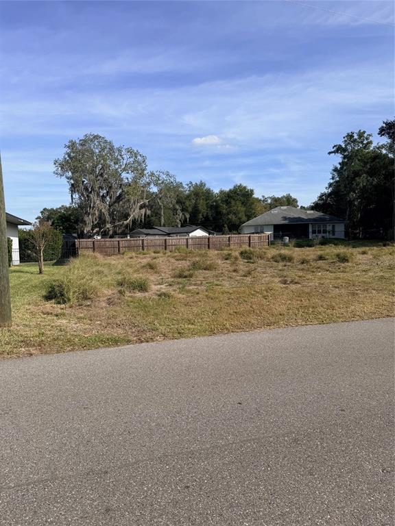 A vacant, grassy residential lot sits next to a paved road and a wooden fence — 1707 TWIN LAKE DRIVE, GOTHA, FL
