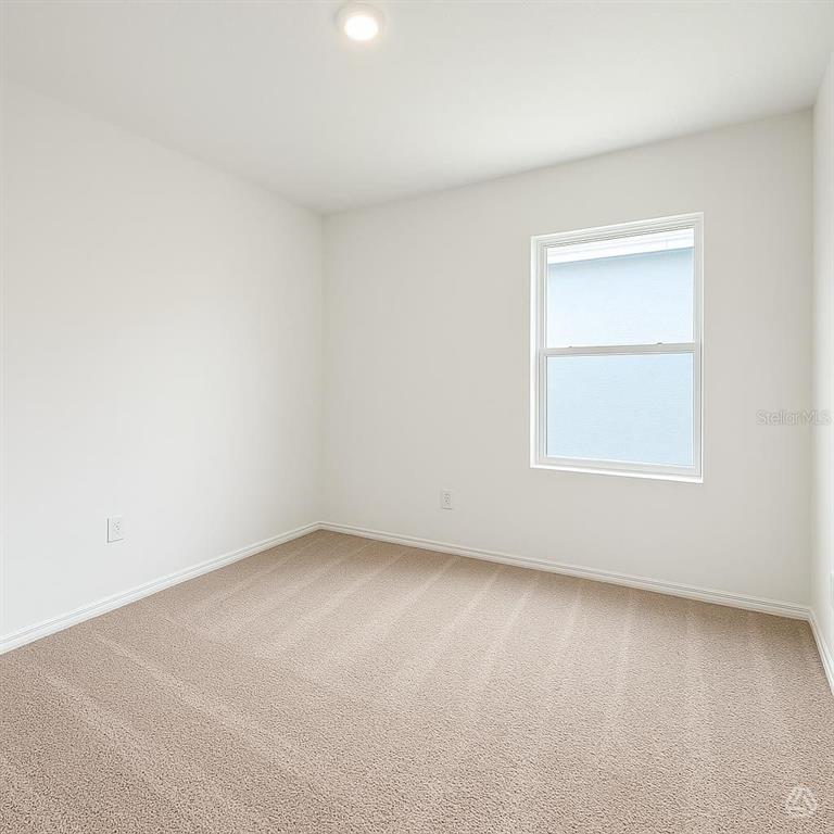 An empty bedroom features white walls, beige carpeting, and a single window — 12910 RED DEER PLACE, PARRISH, FL