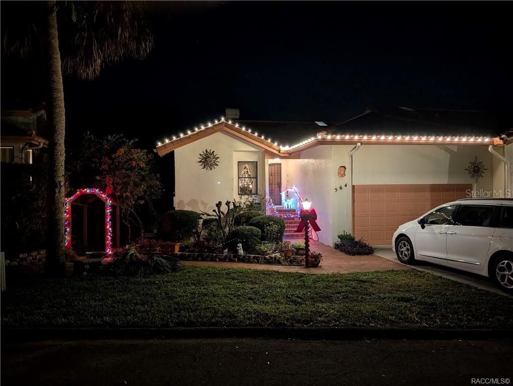 A beige house exterior features a two-car garage, a concrete driveway, and a brick walkway — 564 SAN REMO CIRCLE, INVERNESS, FL