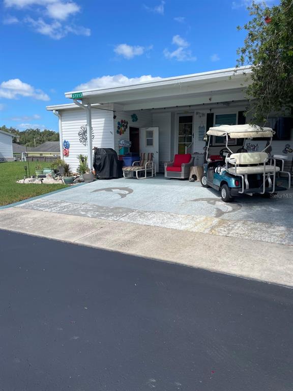 A single-story mobile home with a carport, a golf cart, and a grassy yard — 37513 CAMPO AVENUE, ZEPHYRHILLS, FL