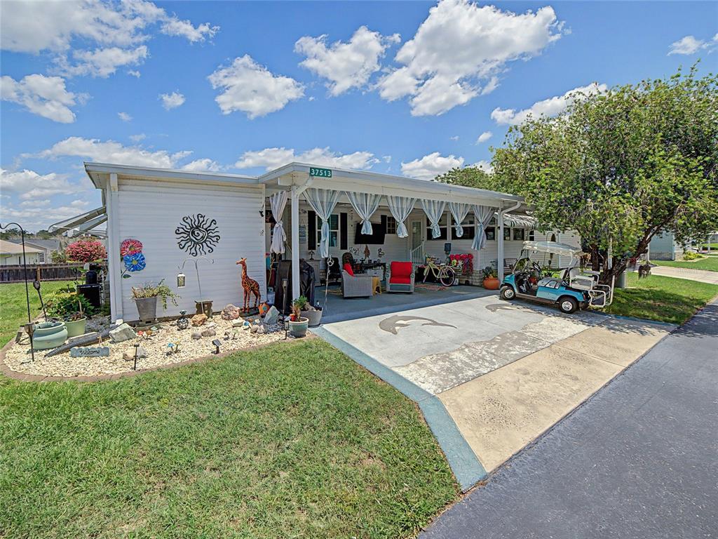A white mobile home with green-striped window awnings sits on a grassy lot — 37513 CAMPO AVENUE, ZEPHYRHILLS, FL