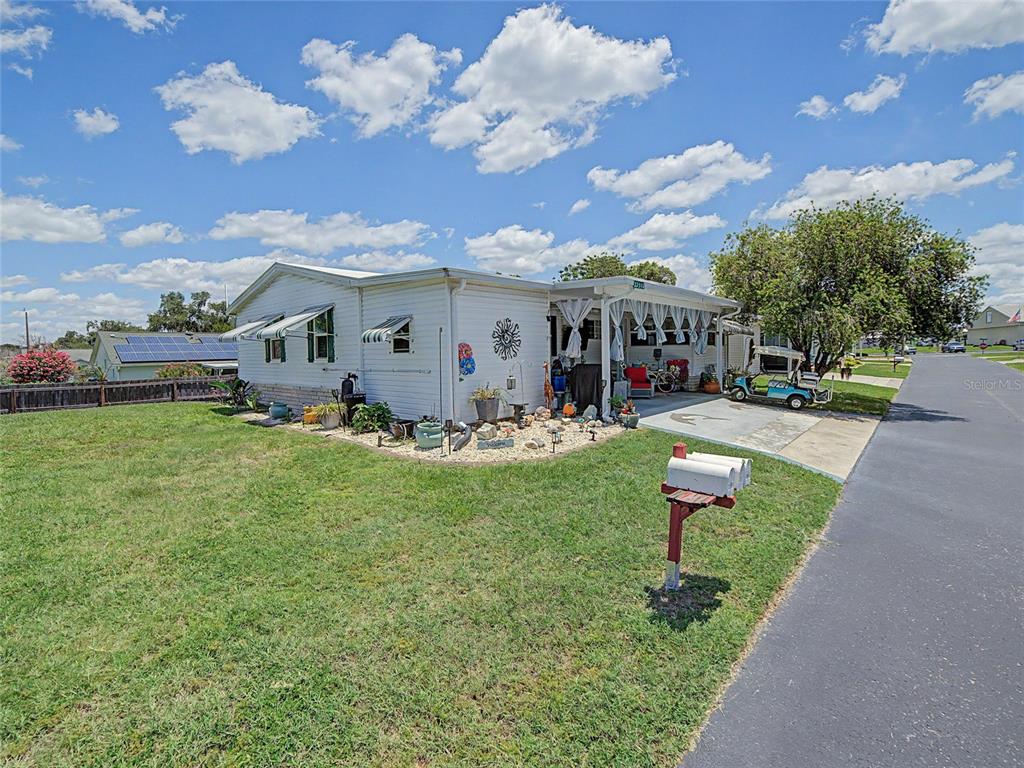 A single-story manufactured home features a covered carport, a golf cart, and a front patio — 37513 CAMPO AVENUE, ZEPHYRHILLS, FL