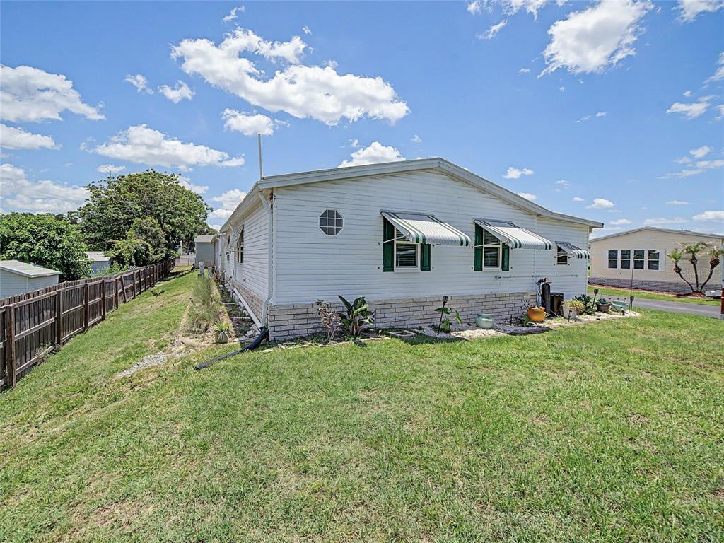 A white mobile home with a screened porch sits behind a large tree and lawn — 37513 CAMPO AVENUE, ZEPHYRHILLS, FL