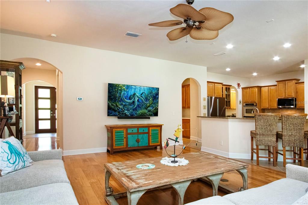 A living room with hardwood floors, a television, a wooden coffee table, and an open kitchen — 1929 24TH STREET CIRCLE W, PALMETTO, FL