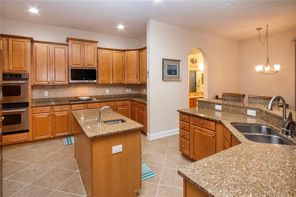 A kitchen with wood cabinets, granite countertops, a center island, and tile flooring — 1929 24TH STREET CIRCLE W, PALMETTO, FL